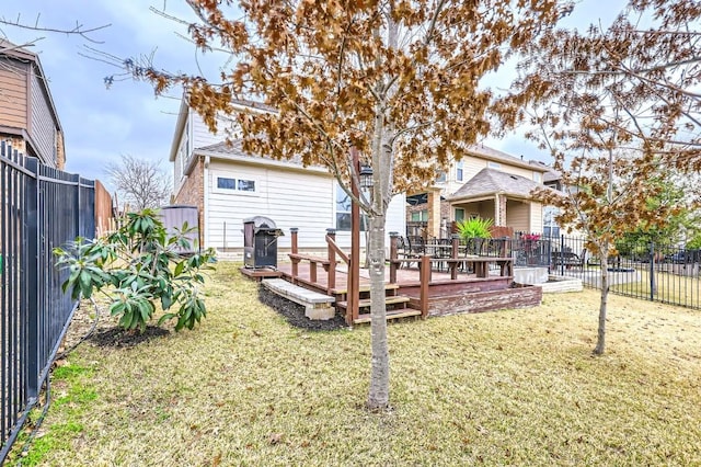 rear view of property with a fenced backyard, a deck, and a lawn