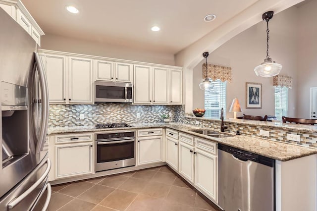 kitchen featuring light tile patterned floors, appliances with stainless steel finishes, light stone countertops, pendant lighting, and a sink