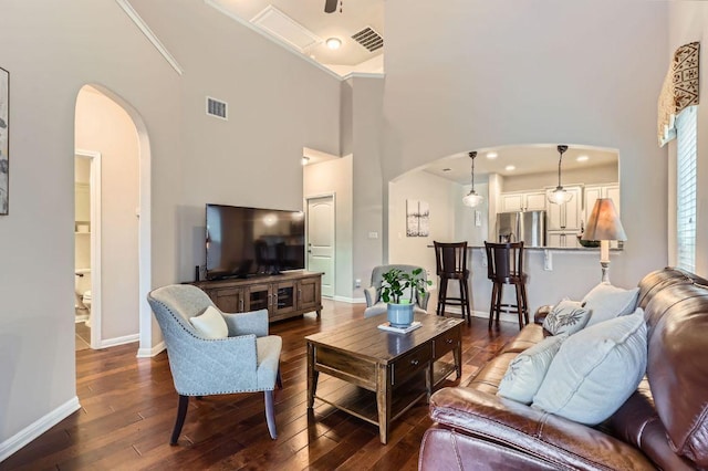 living area with arched walkways, dark wood-style flooring, and visible vents