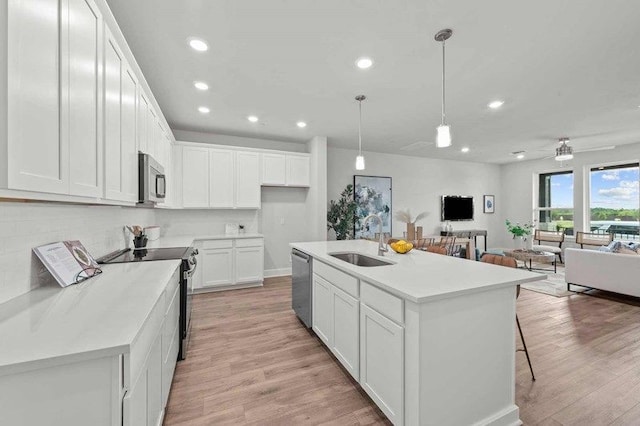 kitchen with sink, white cabinetry, decorative light fixtures, a center island with sink, and appliances with stainless steel finishes