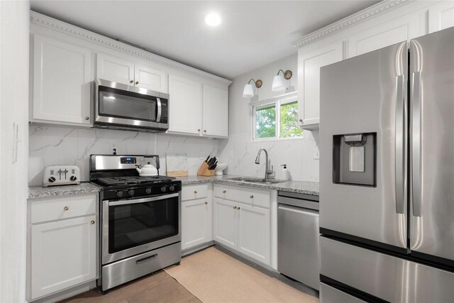5410 Overbrook Dr, Austin, TX 78723 - kitchen with stainless steel appliances, white cabinets, decorative backsplash, light stone counters, and light wood-type flooring