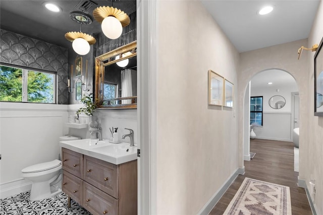 5410 Overbrook Dr, Austin, TX 78723 - bathroom featuring a wainscoted wall, double vanity, recessed lighting, wood finished floors, and wallpapered walls
