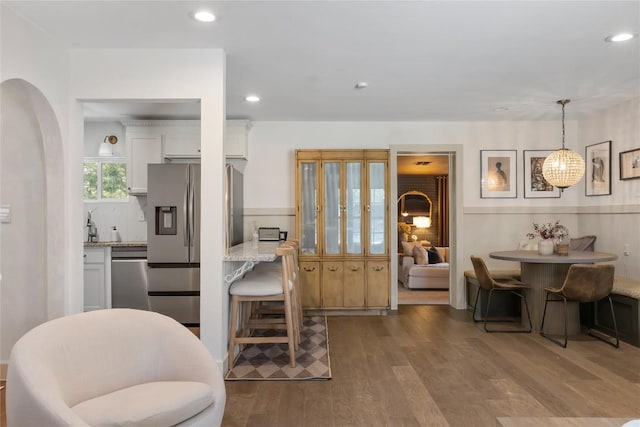 5410 Overbrook Dr, Austin, TX 78723 - kitchen with stainless steel appliances, wood finished floors, white cabinetry, light stone countertops, and decorative light fixtures