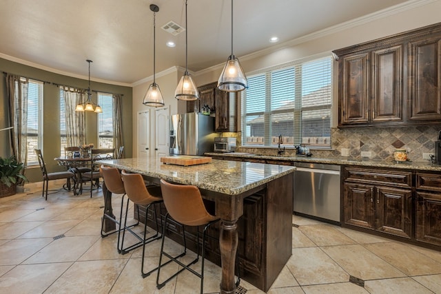 kitchen with a kitchen bar, decorative light fixtures, a center island, appliances with stainless steel finishes, and light stone countertops