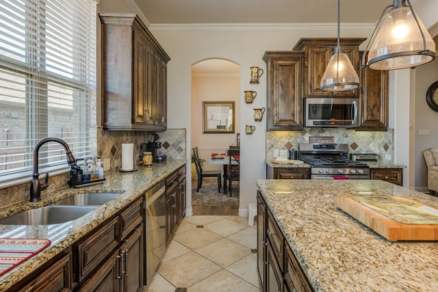 kitchen featuring sink, hanging light fixtures, ornamental molding, stainless steel appliances, and light stone countertops