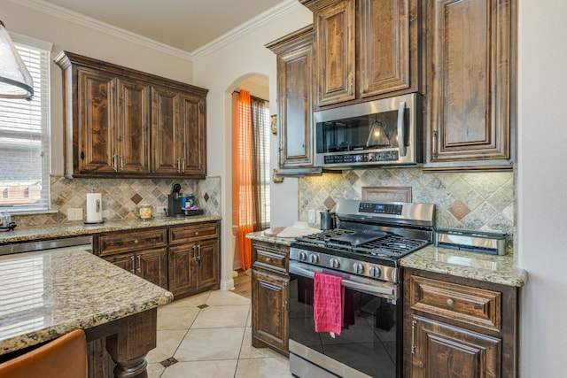 kitchen featuring light stone counters, light tile patterned floors, ornamental molding, and appliances with stainless steel finishes