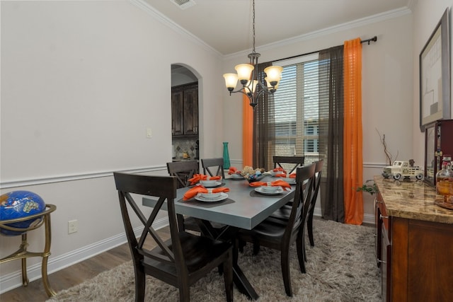 dining space with crown molding, dark wood-type flooring, and a chandelier