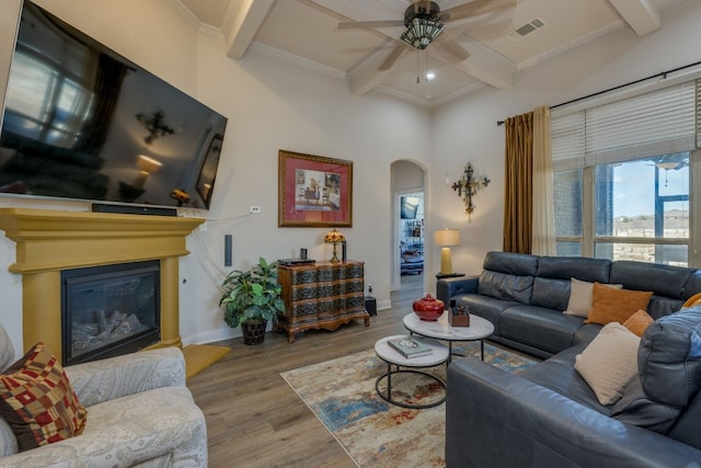 living room with coffered ceiling, crown molding, light hardwood / wood-style flooring, beamed ceiling, and ceiling fan