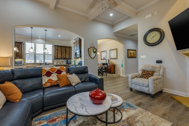 living room featuring wood-type flooring, ornamental molding, coffered ceiling, ceiling fan, and beam ceiling