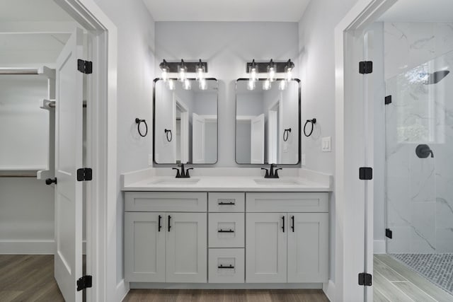 bathroom with wood-type flooring, a shower with door, and vanity