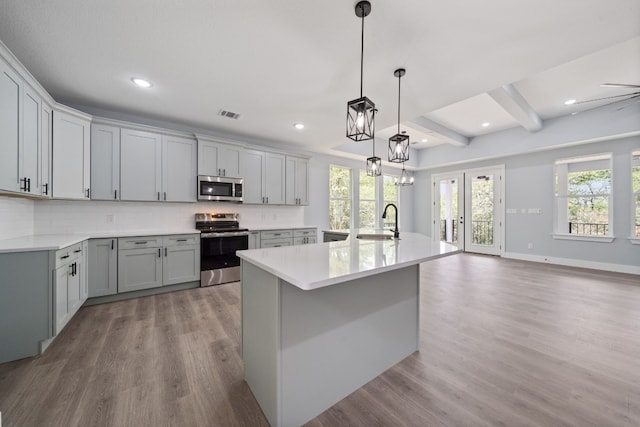 106 Halawa Ct, Bastrop, TX 78602 - kitchen featuring stainless steel appliances, light wood-style flooring, light countertops, decorative backsplash, and gray cabinets