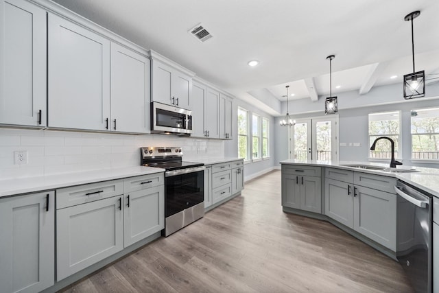106 Halawa Ct, Bastrop, TX 78602 - kitchen with stainless steel appliances, backsplash, light wood-style flooring, light countertops, and decorative light fixtures