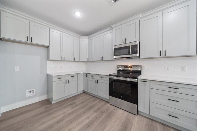 kitchen featuring appliances with stainless steel finishes, light hardwood / wood-style floors, and backsplash