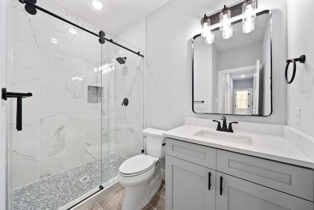 bathroom featuring a shower with door, vanity, and toilet