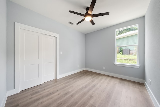 unfurnished bedroom with ceiling fan, light wood-type flooring, and a closet