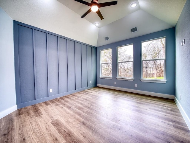 empty room with vaulted ceiling, ceiling fan, and light hardwood / wood-style floors