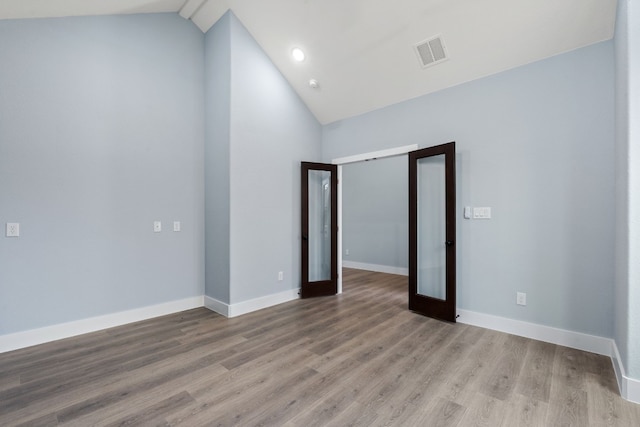 unfurnished room featuring vaulted ceiling, light hardwood / wood-style floors, and french doors