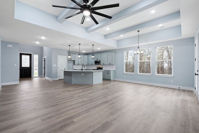 kitchen with an island with sink, light hardwood / wood-style floors, and decorative light fixtures