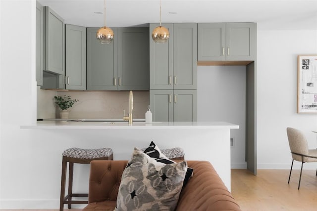 kitchen with pendant lighting, light hardwood / wood-style flooring, kitchen peninsula, and a kitchen bar