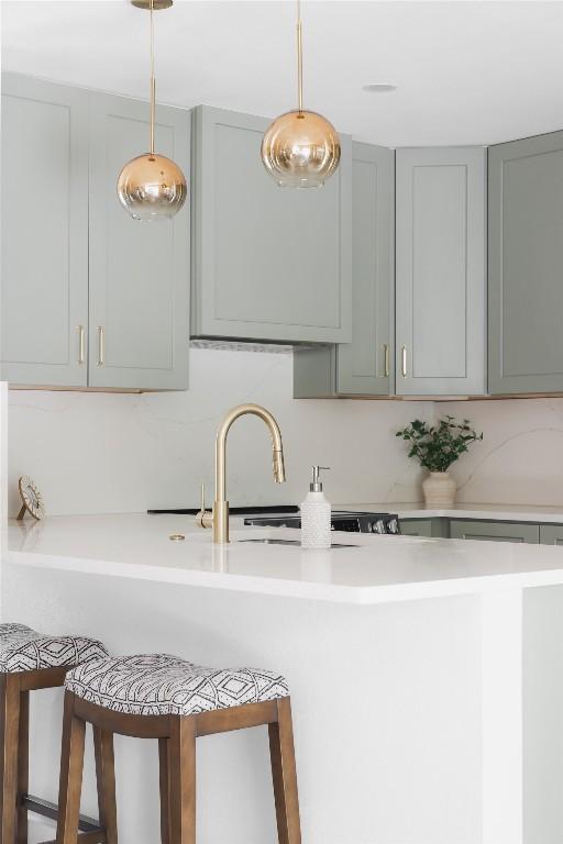 kitchen featuring hanging light fixtures, gray cabinetry, and a kitchen breakfast bar