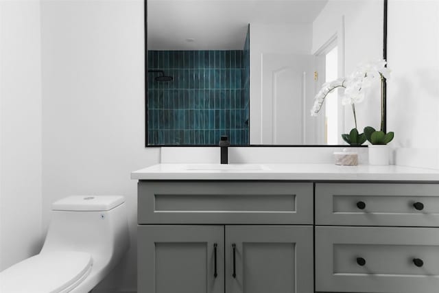 bathroom with vanity, toilet, and a tile shower