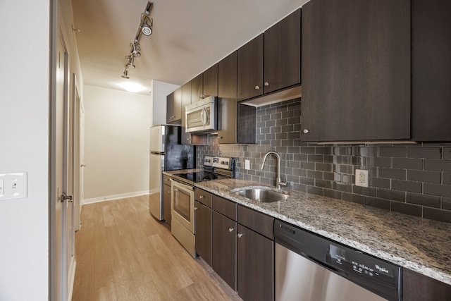 kitchen with sink, dark brown cabinets, light stone countertops, and appliances with stainless steel finishes