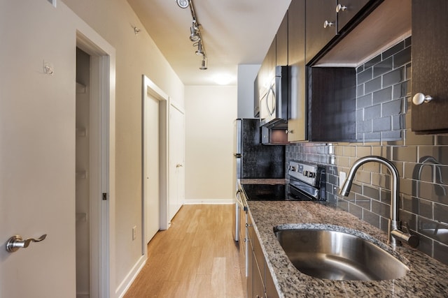 kitchen featuring dark brown cabinetry, stainless steel appliances, sink, and dark stone countertops