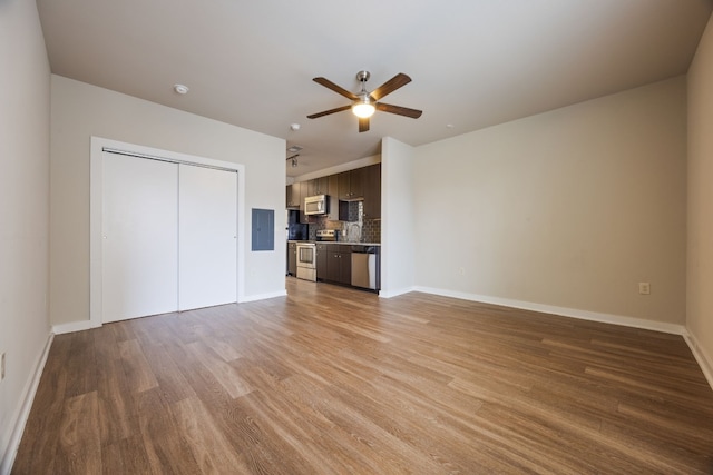 unfurnished living room featuring electric panel, ceiling fan, and light hardwood / wood-style flooring