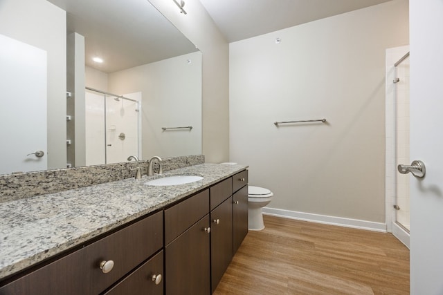 bathroom with an enclosed shower, wood-type flooring, vanity, and toilet