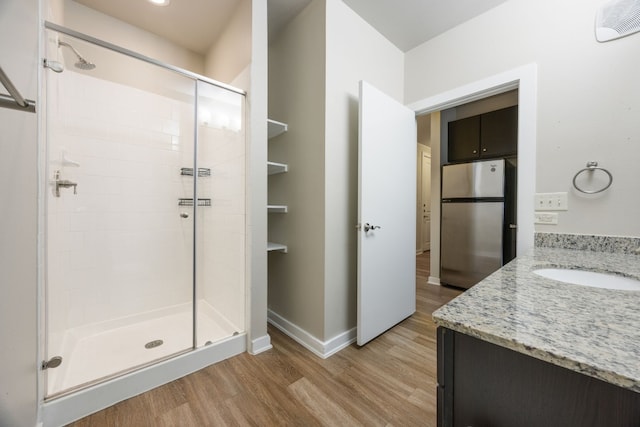 bathroom with hardwood / wood-style flooring, vanity, and a shower with door