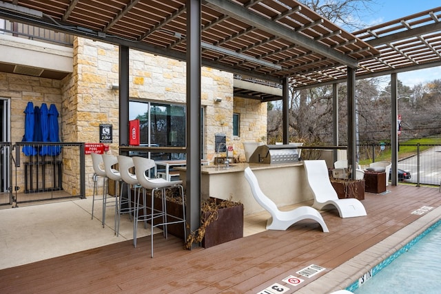 deck with a pool, an outdoor kitchen, exterior bar, and a pergola