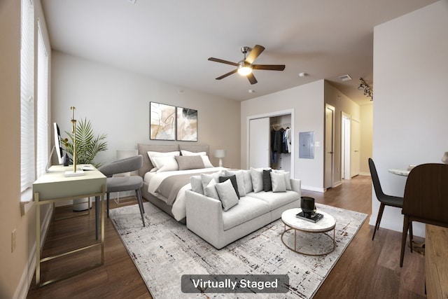 bedroom featuring ceiling fan, electric panel, dark hardwood / wood-style flooring, a walk in closet, and a closet