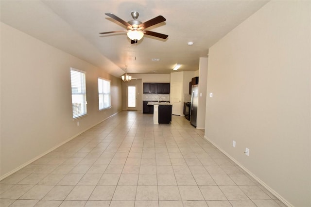 unfurnished living room with ceiling fan with notable chandelier and light tile patterned floors