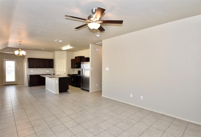 kitchen with light tile patterned floors, stainless steel fridge, ceiling fan with notable chandelier, a center island with sink, and decorative light fixtures