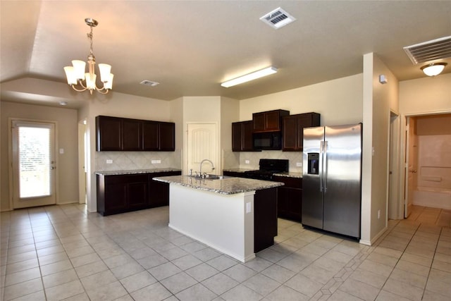 kitchen with sink, light stone counters, hanging light fixtures, an island with sink, and black appliances