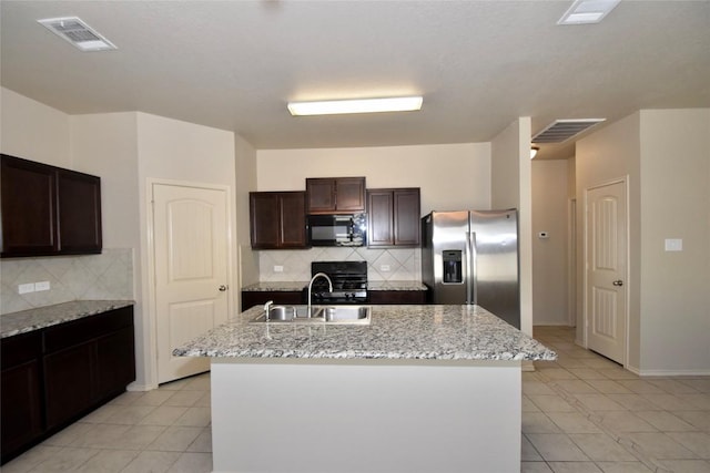 kitchen featuring range, stainless steel fridge, sink, and a center island with sink