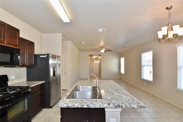 kitchen featuring sink, decorative backsplash, a kitchen island with sink, light tile patterned floors, and black appliances