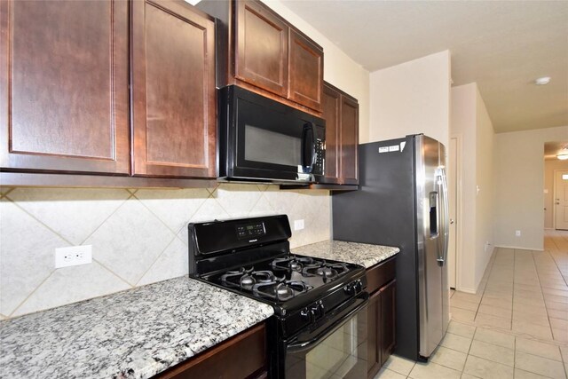 kitchen featuring tasteful backsplash, light stone countertops, light tile patterned floors, and black appliances