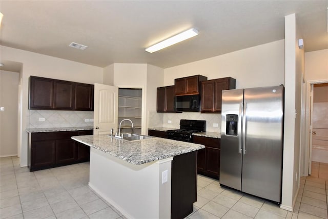 kitchen featuring sink, light tile patterned floors, a kitchen island with sink, dark brown cabinetry, and black appliances