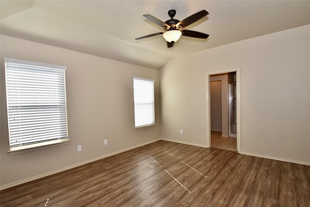 empty room with lofted ceiling, dark hardwood / wood-style floors, and ceiling fan