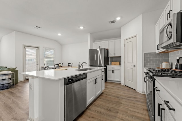 kitchen featuring sink, white cabinetry, light hardwood / wood-style flooring, stainless steel appliances, and a kitchen island with sink