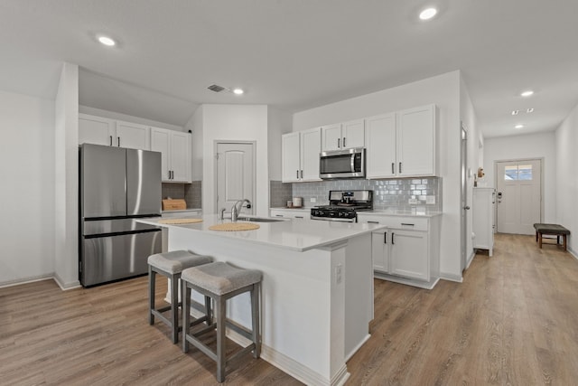 kitchen featuring a kitchen island with sink, sink, white cabinets, and appliances with stainless steel finishes