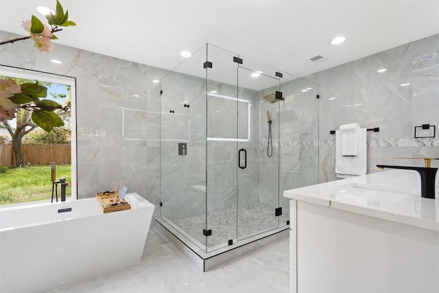 bathroom with vanity, separate shower and tub, and tile walls