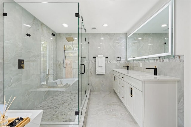 bathroom with vanity, shower with separate bathtub, and tile walls