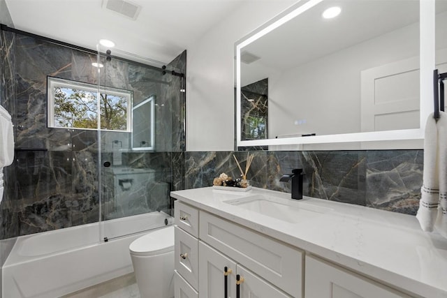 full bathroom with tasteful backsplash, tile walls, shower / bath combination with glass door, vanity, and toilet