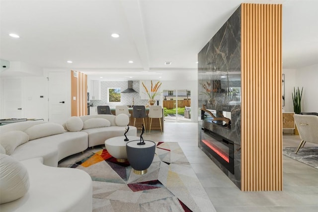 living room featuring beam ceiling and a large fireplace