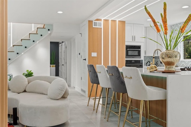 kitchen featuring white cabinetry, double wall oven, and decorative backsplash