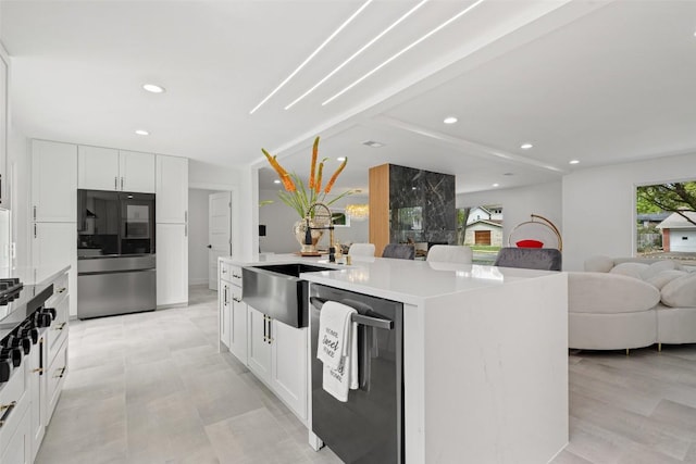 kitchen with sink, stainless steel refrigerator, dishwasher, a center island, and white cabinets