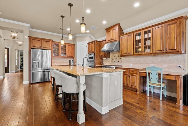 kitchen featuring a breakfast bar, light stone counters, hanging light fixtures, a center island with sink, and appliances with stainless steel finishes