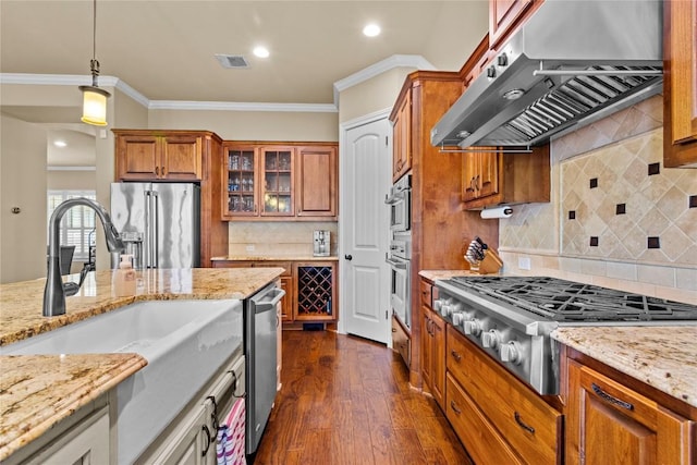 kitchen featuring light stone counters, extractor fan, hanging light fixtures, and appliances with stainless steel finishes